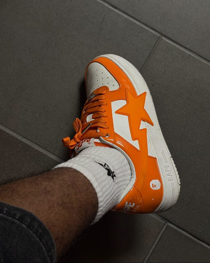 Orange and white sneaker with star design on a gray tiled floor